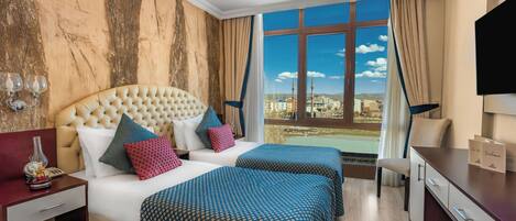 A hotel room with a large bed, two bedside tables, a TV, and a view of a cityscape through a large window.