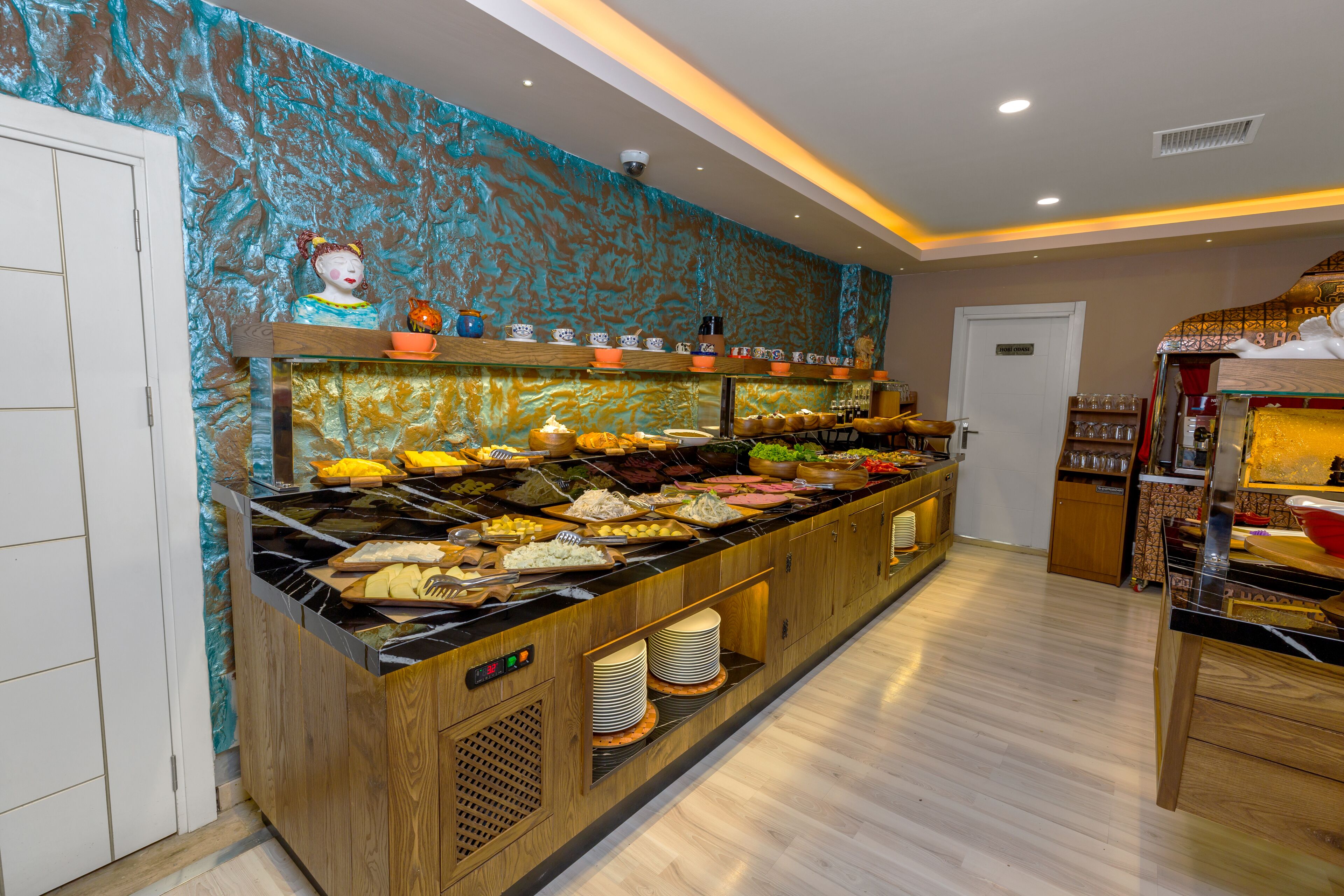 A buffet area with a variety of food items, a wooden counter, and a decorative wall with a blue pattern.