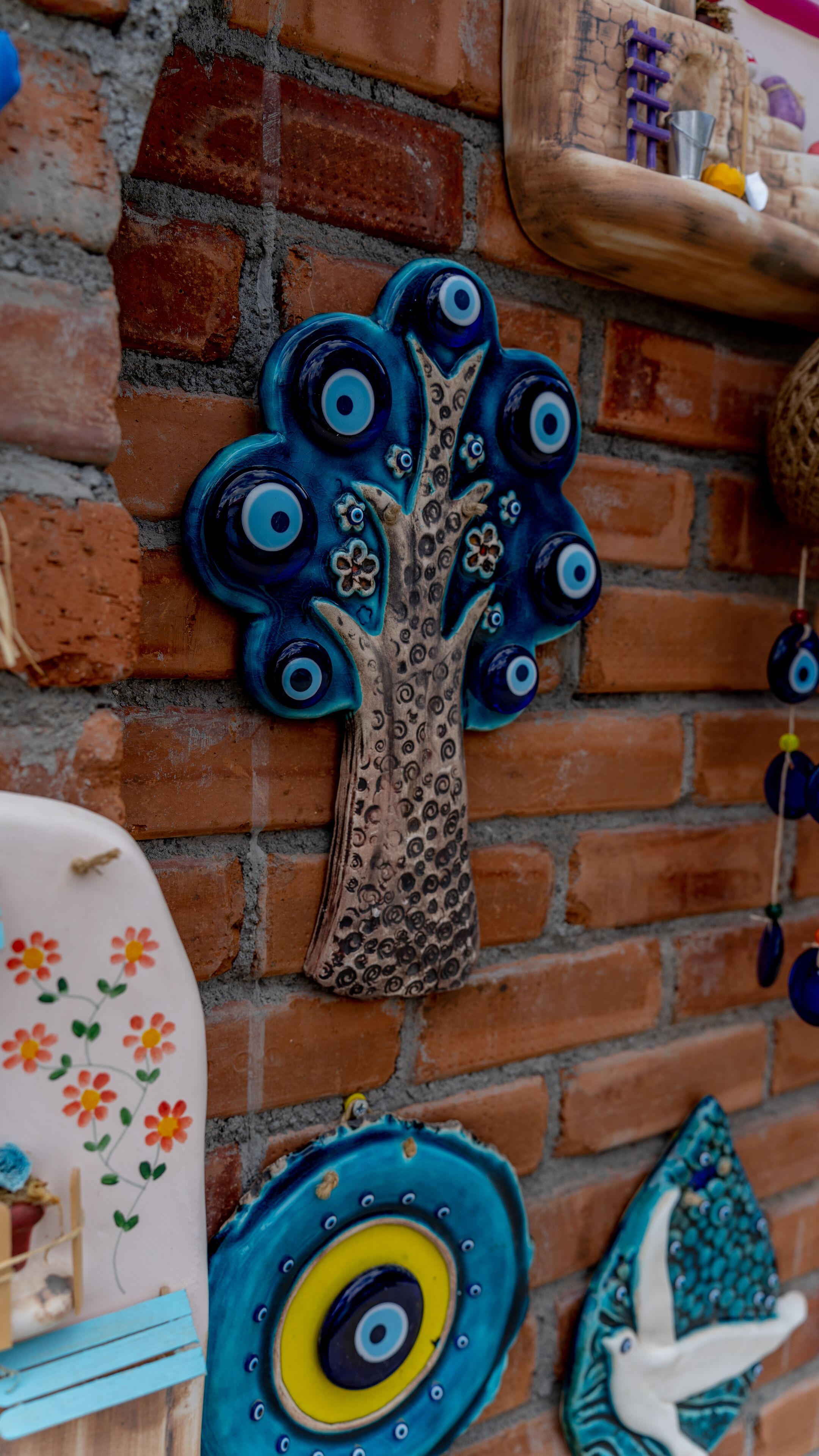 A wall with a blue tree decoration, a bird sculpture, and a plate with floral designs.