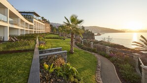 Ett hotell vid kusten med modern design, med en gångväg som leder till en palm och en utsikt över havet.
