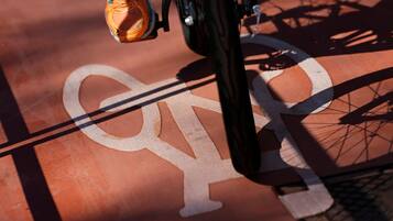 A bicycle with a white frame and orange details, positioned over a red surface with a white bicycle symbol.
