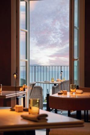 A dining area with tables and chairs, a view of the sky, and a balcony with a railing.