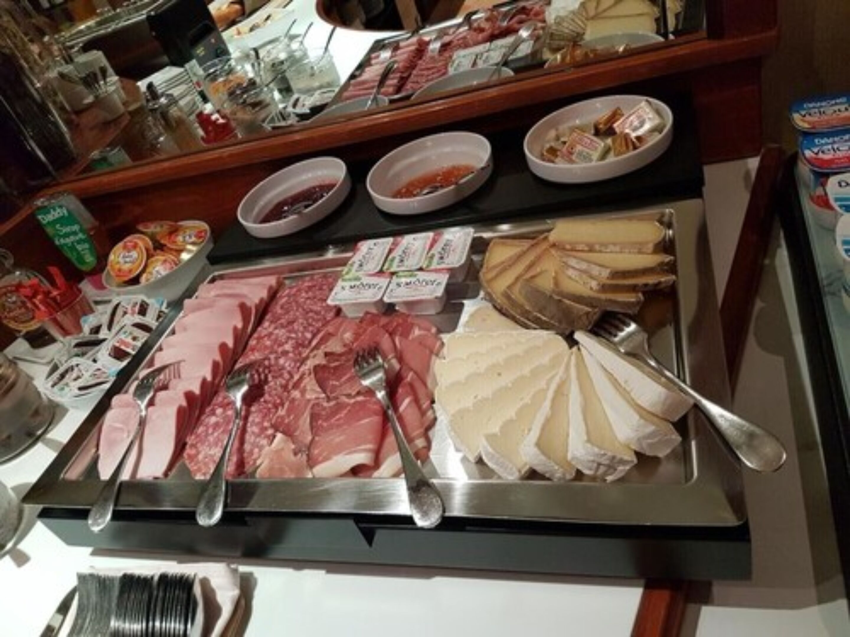 Un bufé con diversos tipos de carne, quesos y salsas.