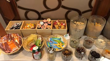 A buffet table with various food items including jars of preserves, a bottle of honey, and baskets of snacks.