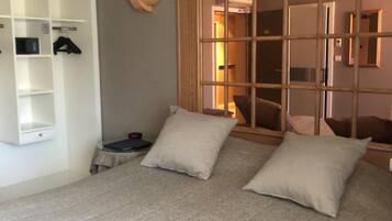 A bedroom with a bed, two pillows, a wardrobe, and a nightstand.