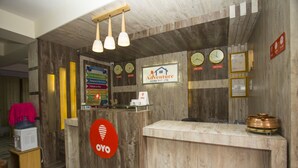 A reception desk with a wooden finish, a sign for 'Adventure Home Pvt. Ltd.', clocks displaying time, and a 'Free Information' sign.