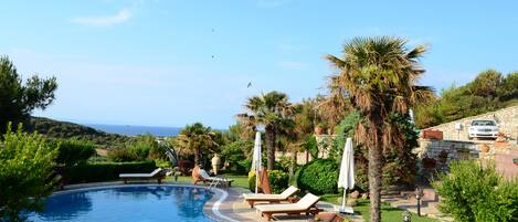 Een buitenzwembad, ligstoelen bij het zwembad