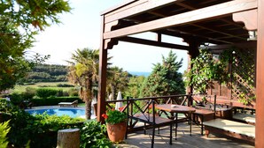 A wooden pergola with a pool and outdoor seating area. - Ada Bacchus Hotel (Bozcaada)