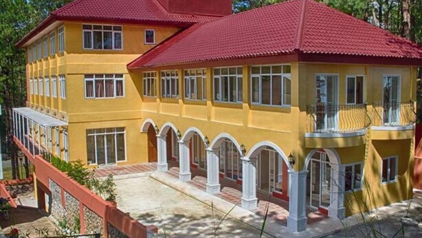 A multi-story yellow building with red roofs, white columns, and a covered walkway. - Arc Residences (Baguio)