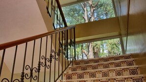 A staircase with ornate metal railings and patterned steps, leading to a balcony with a view of trees. - Arc Residences (Baguio)