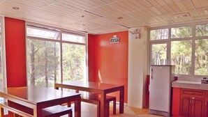 A room with a dining table, chairs, a refrigerator, and a window with an exit sign. - Arc Residences (Baguio)
