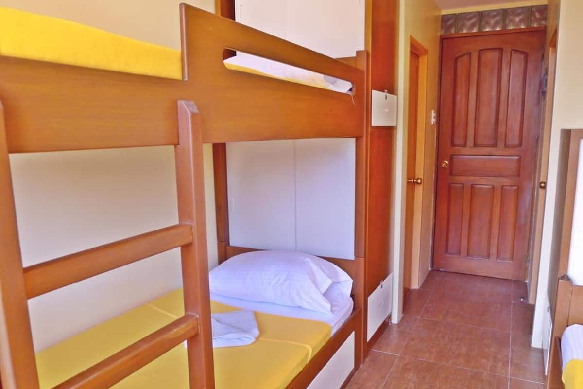 A bunk bed room with wooden frames and yellow bedding.