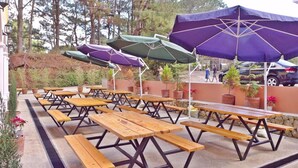 Outdoor picnic tables with umbrellas and potted plants. - Arc Residences (Baguio)