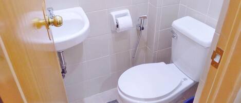 Un baño pequeño y limpio con inodoro blanco, lavabo y ducha.
