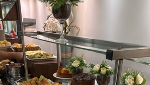 Un bufé con diversas opciones de comida, incluyendo pasteles, sándwiches y postres.