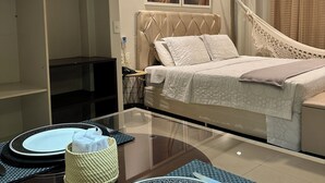 Una habitación de hotel moderna con una cama, mesita de noche y una mesa de vidrio con platos y cubiertos.