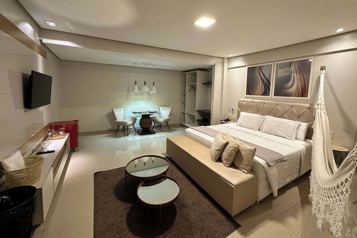 Un dormitorio moderno con una cama grande, mesitas de noche, un televisor, un escritorio y un armario.