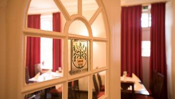Een restaurantinterieur met een raam waarop een logo en naam staan.