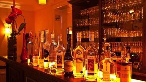 Zona de bar con diferentes botellas de licores y vasos.