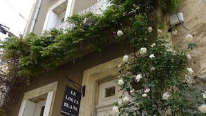 Un edificio con un cartel que dice "LE LOGIS BLANG" y una puerta blanca con cerradura.