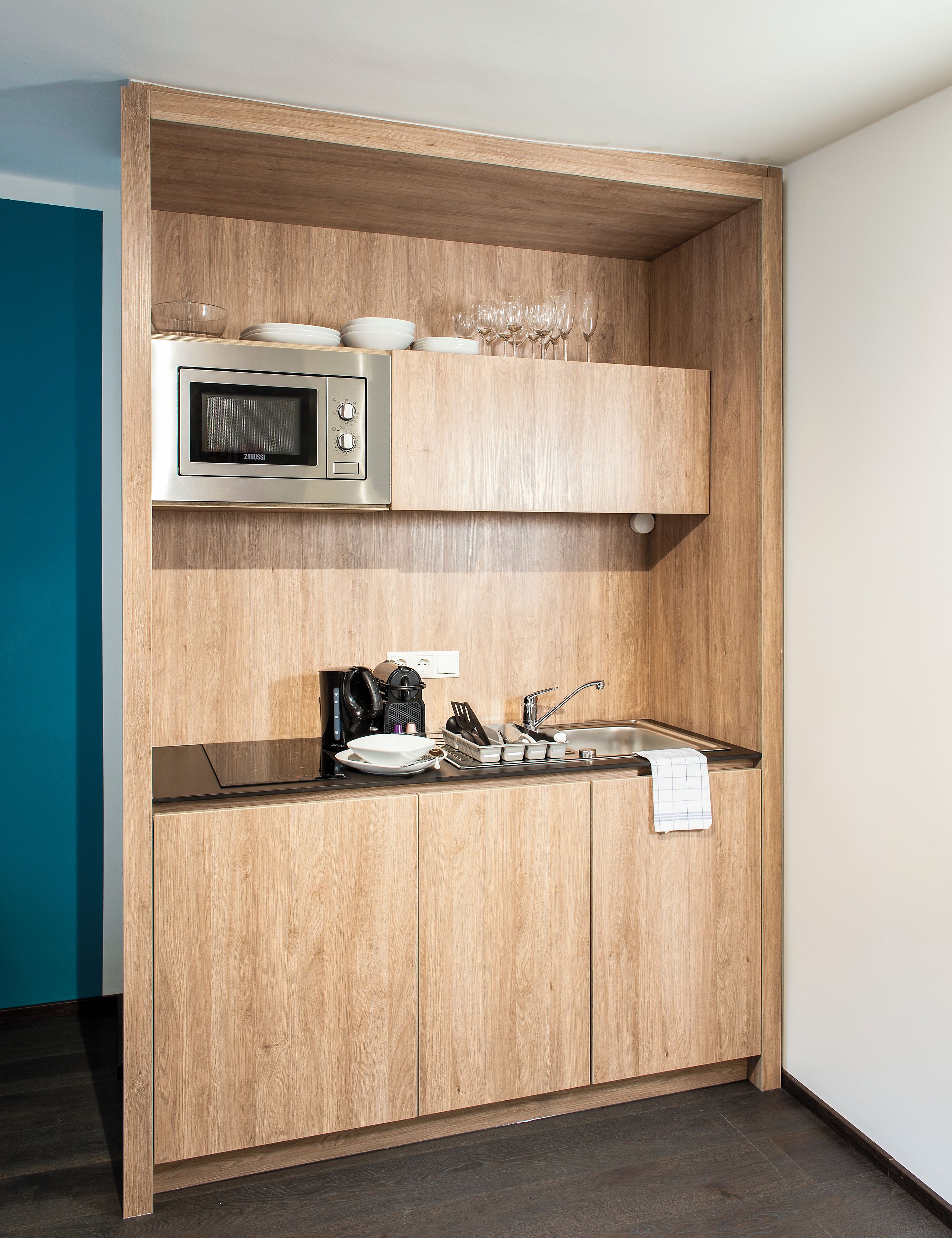 A compact kitchen with a built-in microwave, a coffee maker, and a sink.