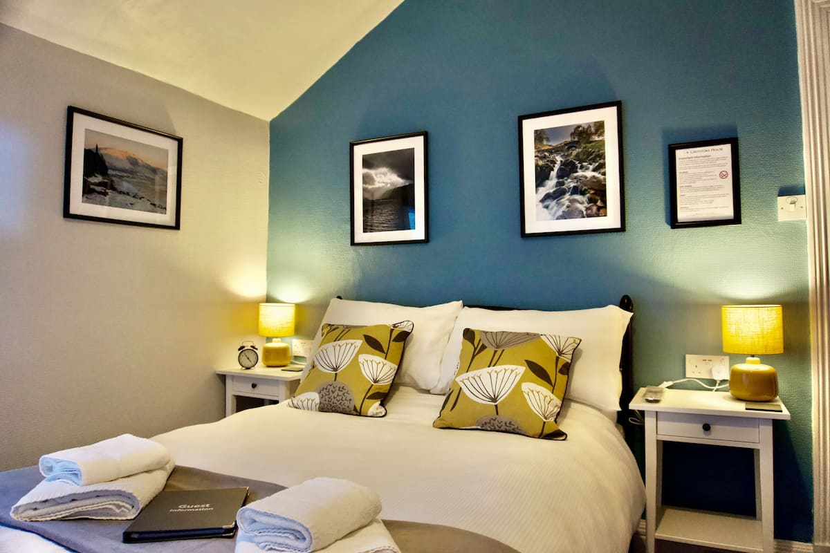 Een hotelkamer met een bed, twee nachtkastjes en een muur met ingekaderde foto's.