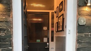 Una porta negra amb un tancament de codi numèric, un graó metàl·lic i un estriat.