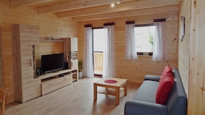 Une pièce aux murs lambrissés, avec un téléviseur, un canapé et une petite table.