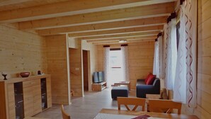 Un intérieur en bois comprenant un coin repas, un canapé et un téléviseur à l’arrière-plan.