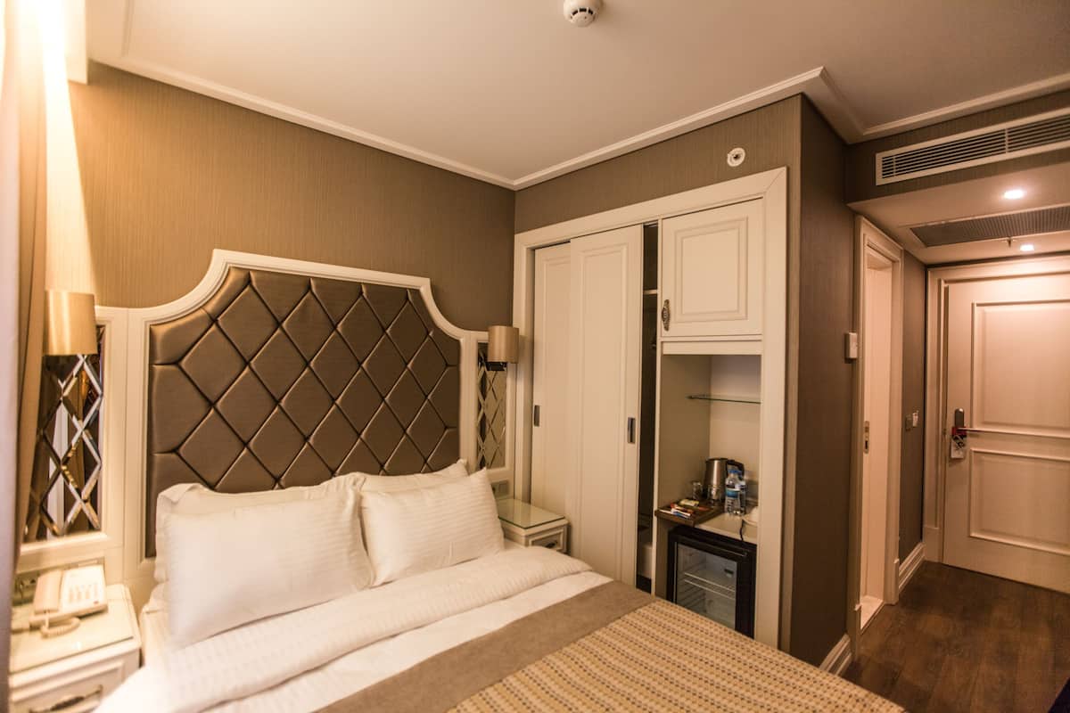 A hotel room with a large bed, a wardrobe, a bedside table, and a nightstand.