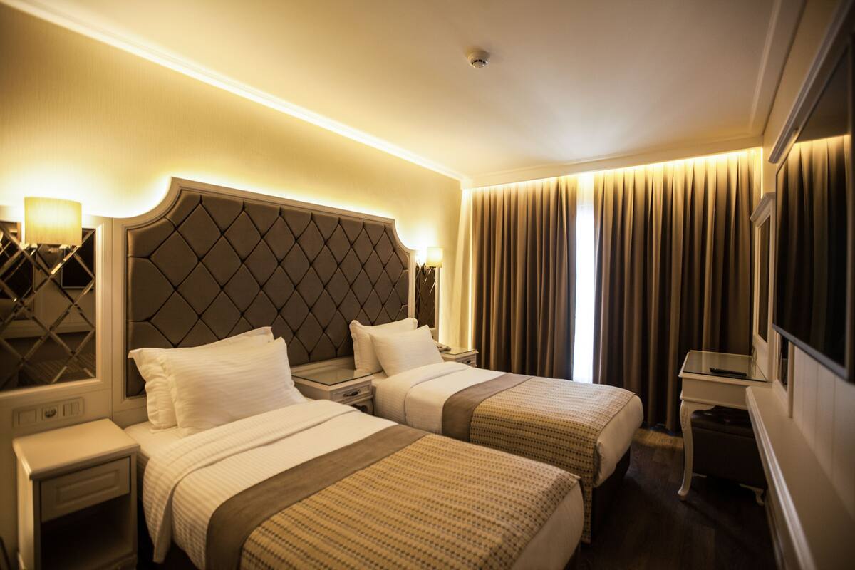 A hotel room with two beds, a nightstand, a desk, and a television.