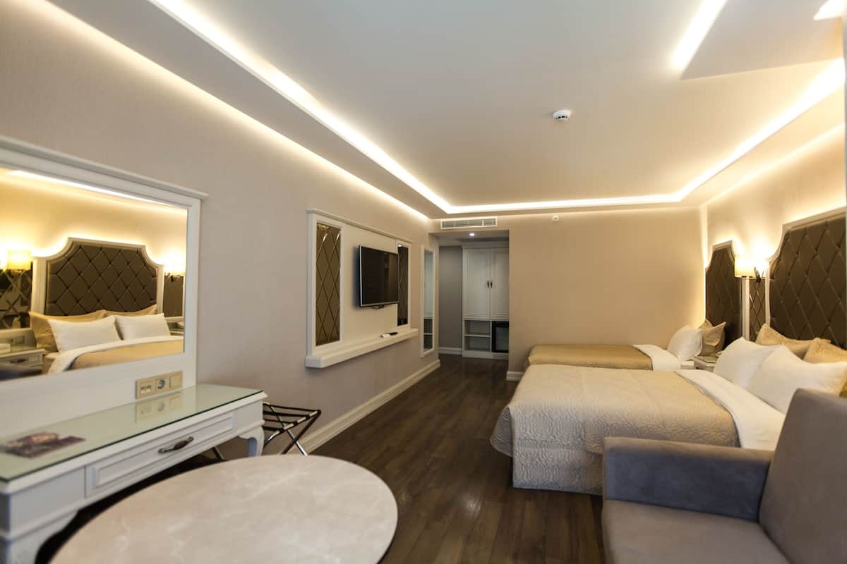 A modern hotel room with a large bed, a desk, and a mirror.