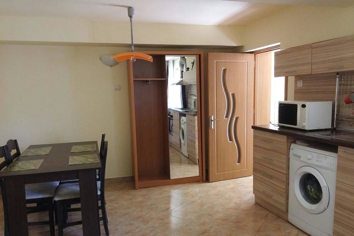 A compact kitchen with a washing machine, a microwave, and a dining area with a table and chairs.