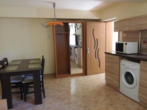 A compact kitchen with a washing machine, a microwave, and a dining area with a table and chairs.