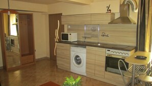 A compact kitchen with a washing machine, microwave, and oven. - Varna Apartments (Varna)