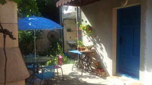 A patio area with a table and chairs, a blue umbrella, potted plants, and a blue door. - Varna Apartments (Varna)