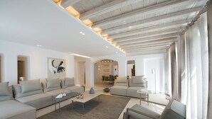 Una sala de estar moderna con un sofá gris, una mesita de centro y un sillón gris. En el fondo, hay una zona de comedor con una mesa y sillas.