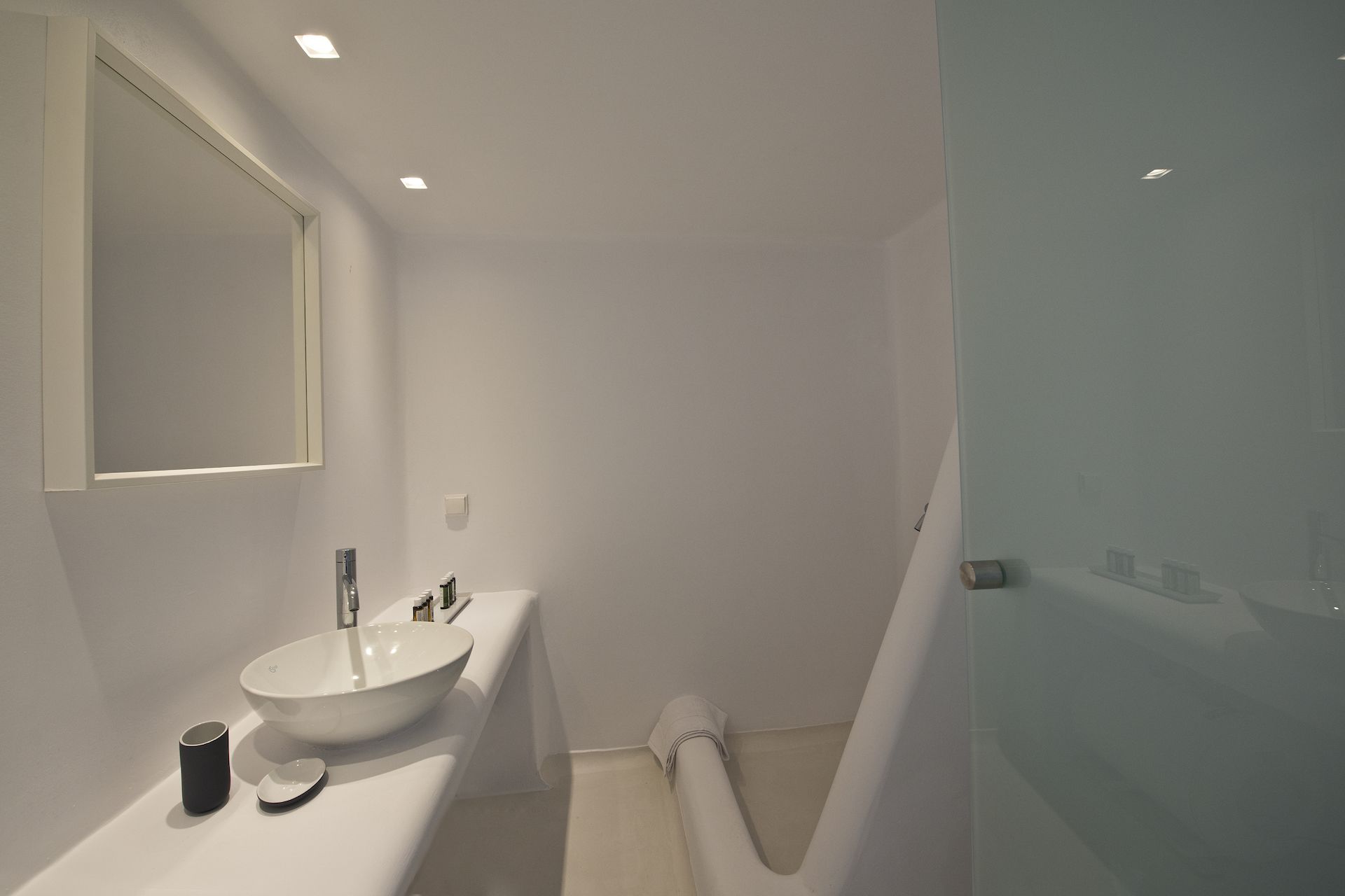 A modern bathroom with a white sink, mirror, and shower.