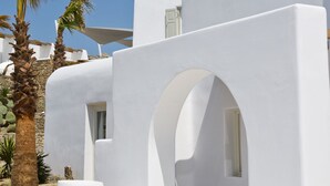 Un edificio blanco con un arco de entrada, palmeras y un cielo azul despejado.