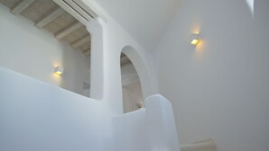 Una escalera blanca con techo de madera y dos luces empotradas en la pared.