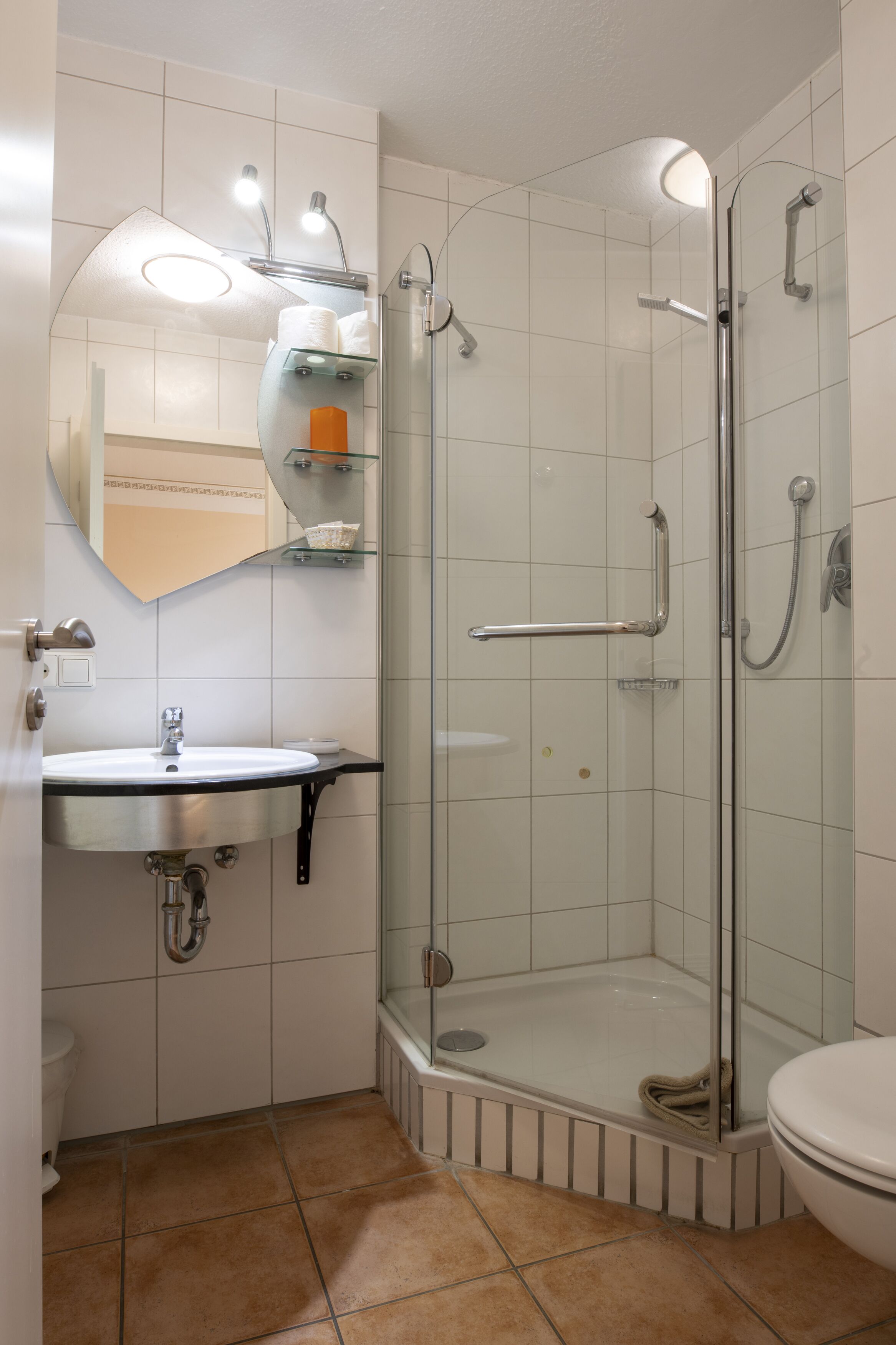 A bathroom with a glass-enclosed shower, a sink with a mirror above, and a toilet.