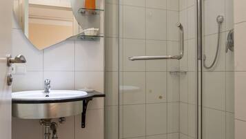 A bathroom with a glass-enclosed shower, a sink with a mirror above, and a toilet.