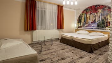 A hotel room with a bed, a small table, and a window with curtains.