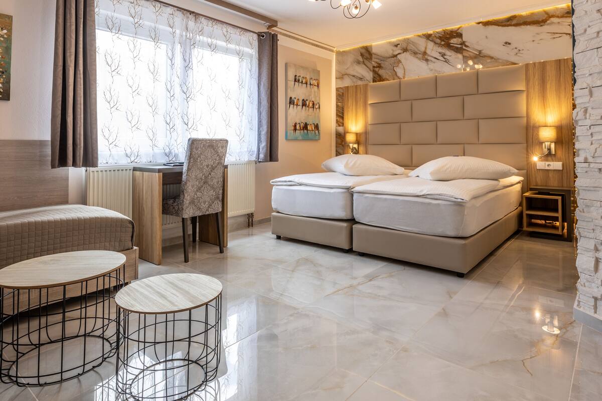 A modern bedroom with a bed, a desk, and two round tables.