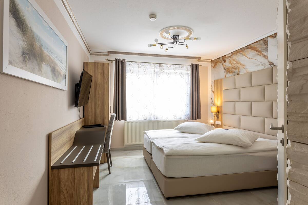 A modern hotel room with a bed, a desk, and a chair.