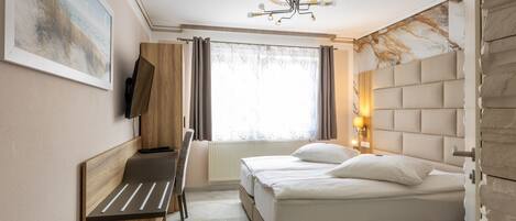 A modern hotel room with a bed, a desk, and a chair.