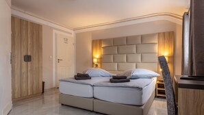 A modern bedroom with a large bed, wooden wardrobe, and a nightstand. - Hotel Restaurant Meteora (Tuebingen)