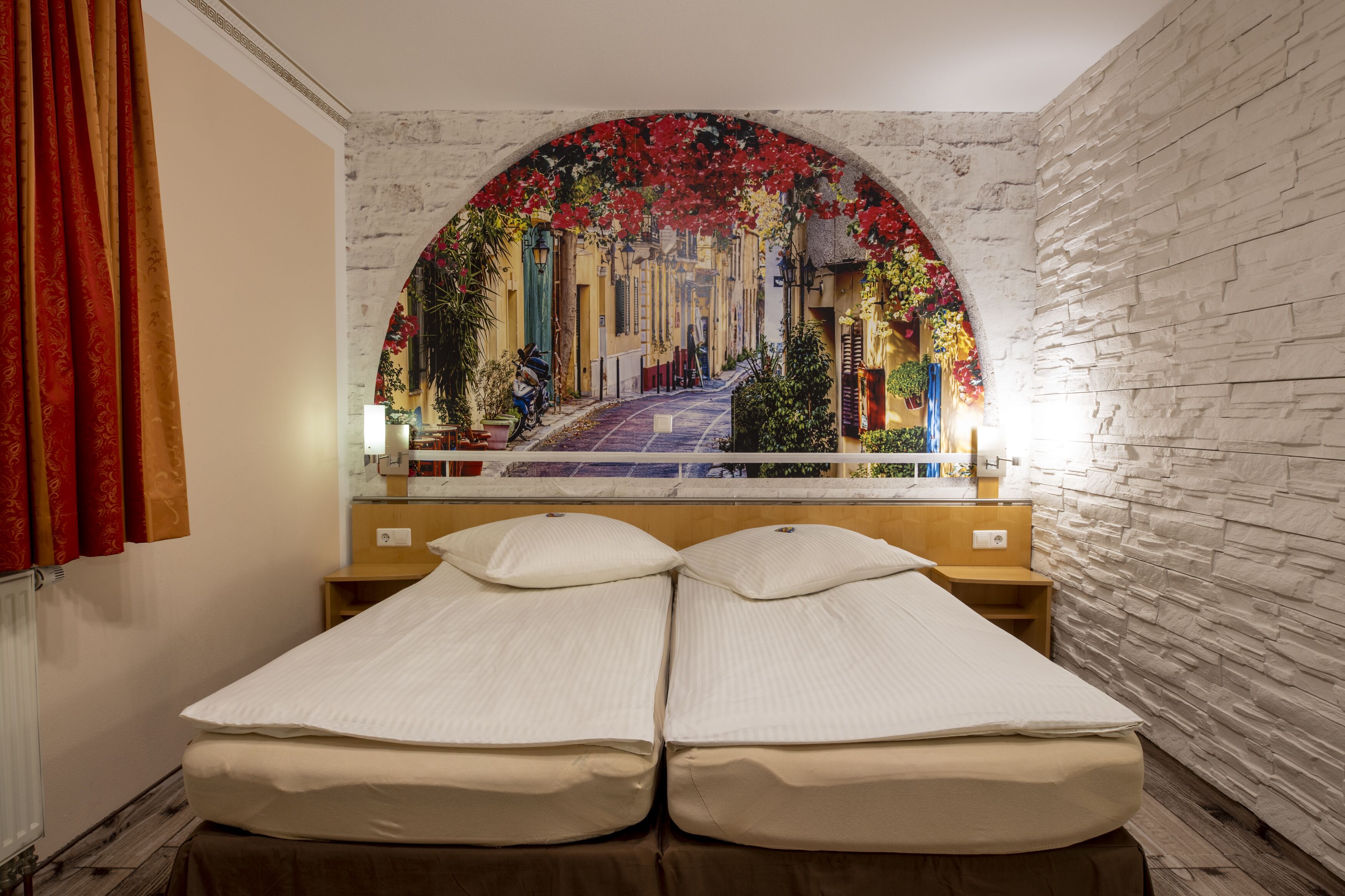 A double bed with a view of a street through an arched window.