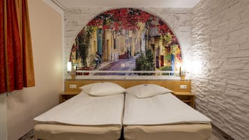 A double bed with a view of a street through an arched window.