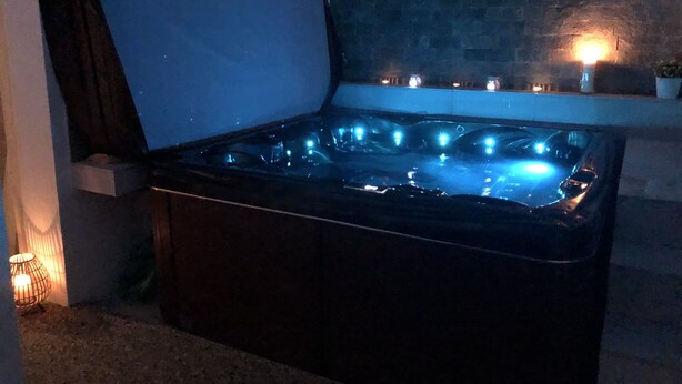 Uma banheira de hidromassagem com interior escuro e chão revestido de azulejos.
